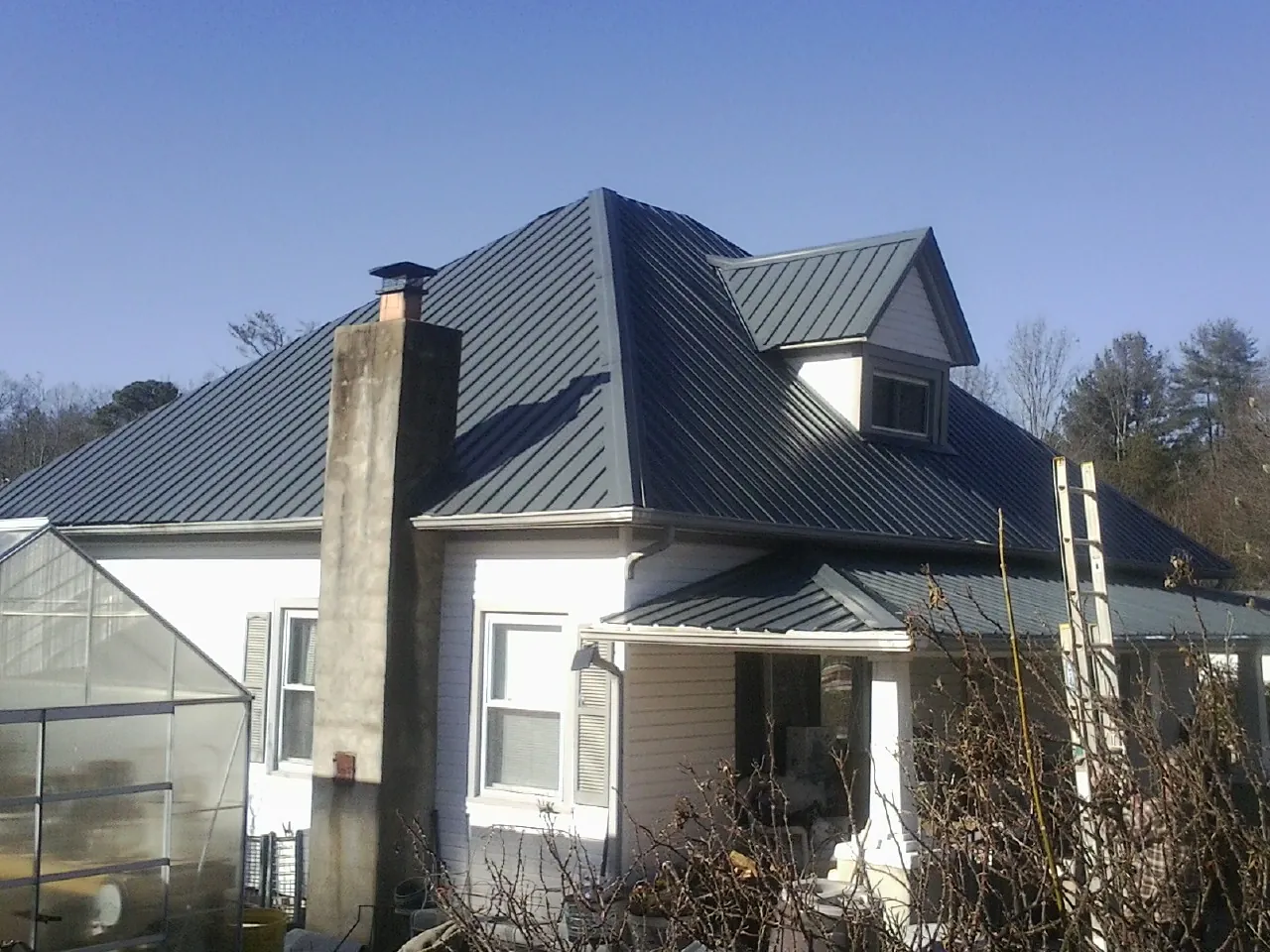 Dark blue standing seam metal roof on a white farmhouse with dormer — Slate & Tile Roof Repair by Roofing Brothers in Blakely Island