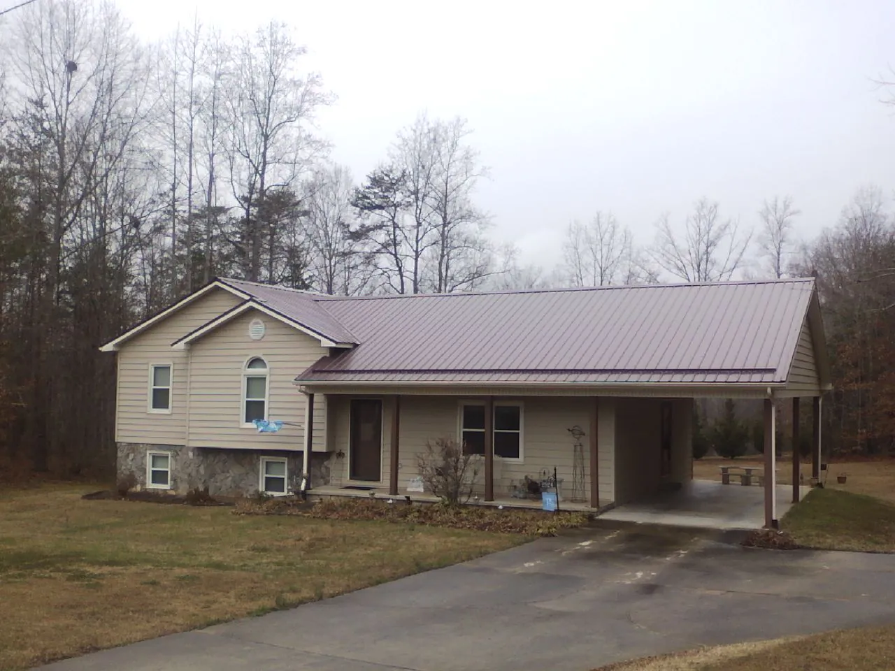 Burgundy metal roof on a tan split level home with an attached carport in Blakely Island