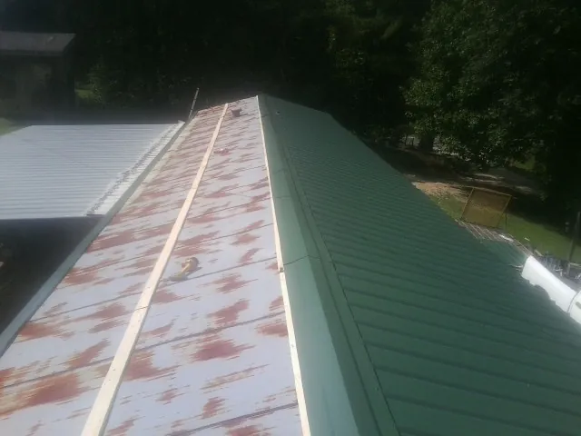 Old rusted panels beside newly installed green metal roofing — Wind Damage Roof Repair by Roofing Brothers in Blakely Island