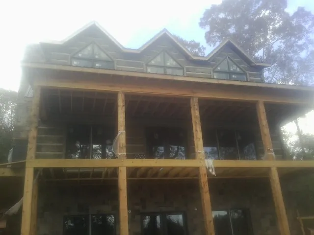 Dormers and porch framing on a large log home under construction — Roof Coating work by our crew in Blakely Island