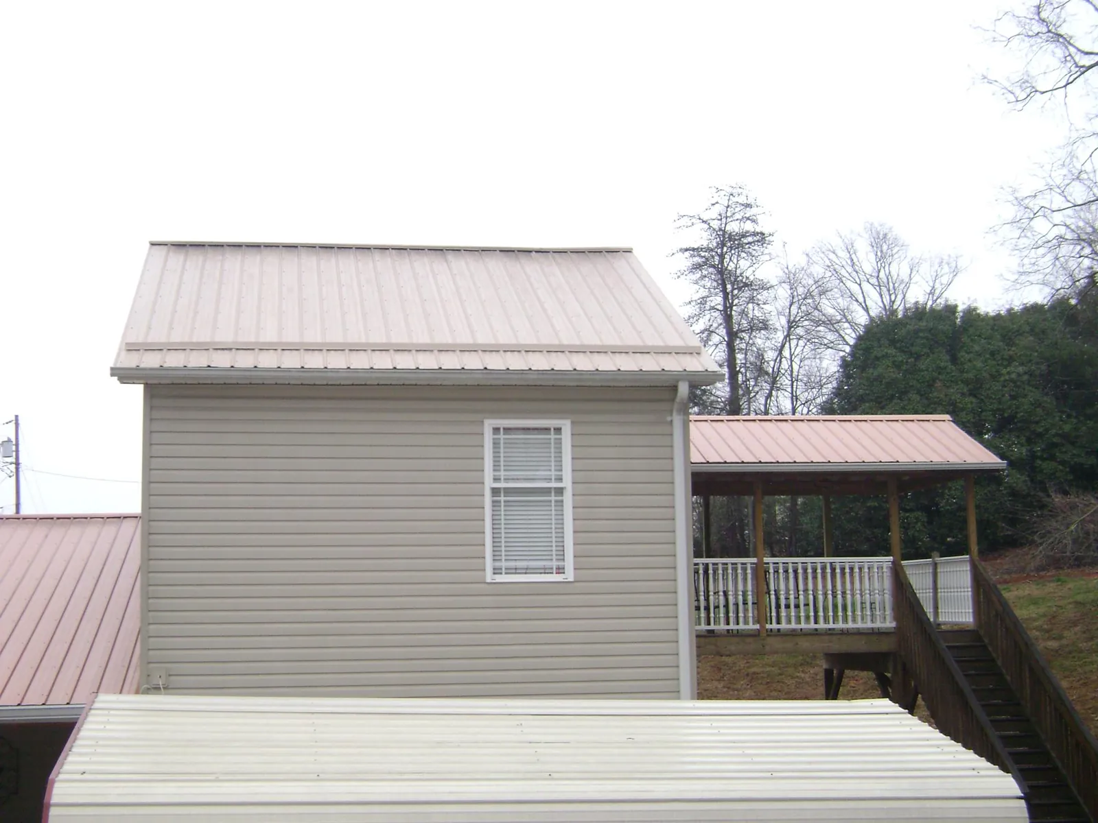 Tan metal roofs on a two story addition and attached porch, from a Roof Replacement job in Blakely Island