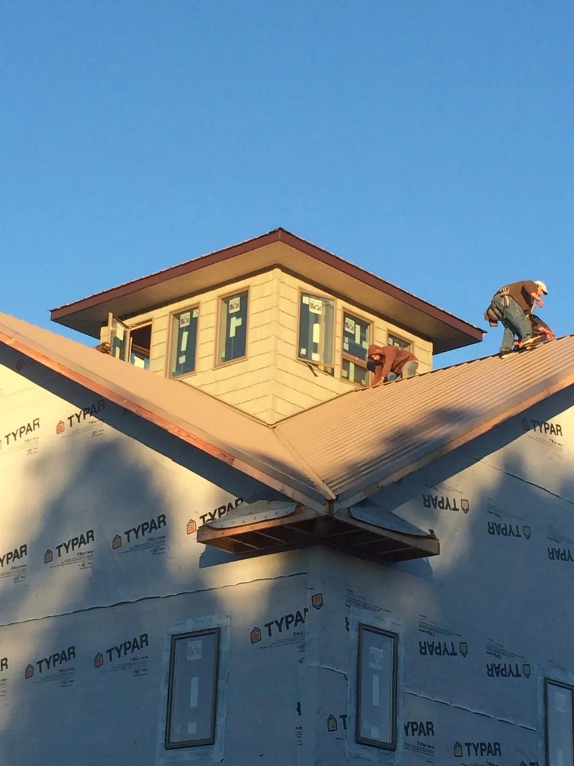 Roofers working around a rooftop cupola on a new metal roof at sunset — Roof Waterproofing in Blakely Island by Roofing Brothers